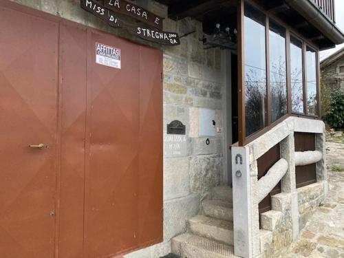 a building with a red door and stairs in front at Casa vacanza da Berto in Stregna