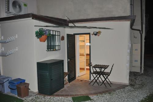 un pequeño edificio blanco con una puerta y una silla en La casina, en Pietrasanta