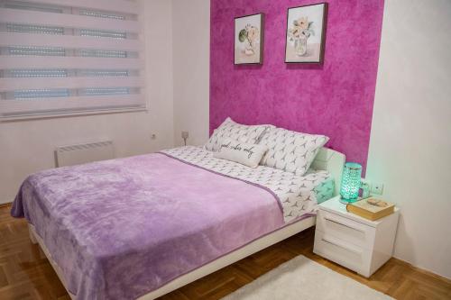 a bedroom with a bed with a purple wall at Apartment Queen 2 in Trebinje
