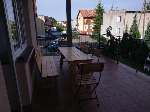 patio z drewnianym stołem i krzesłami na balkonie w obiekcie Grodzisko pokoje do wynajęcia w mieście Krynica Morska
