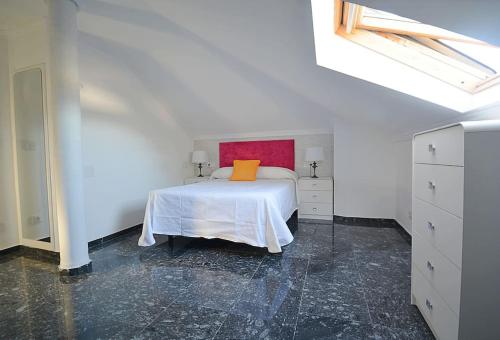 ein weißes Schlafzimmer mit einem Bett mit orangefarbenem Kissen darauf in der Unterkunft Dúplex da Pedra e da Auga in Meis