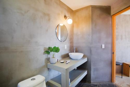 a bathroom with a sink and a toilet and a mirror at Casas VV in Valle de Guadalupe