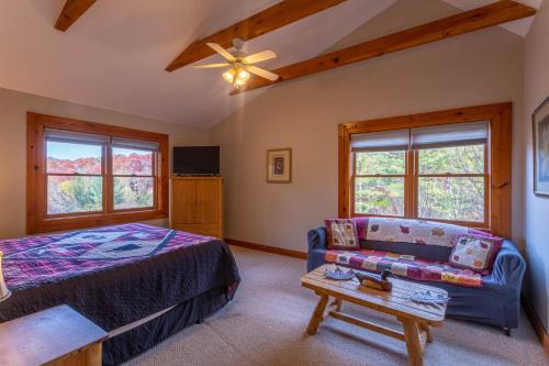 a bedroom with a bed and a couch and windows at River Ridge in Boone