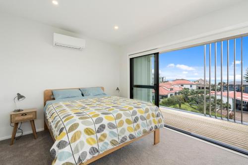 a bedroom with a bed and a large window at Coastal Paradise - Orewa Holiday Home in Orewa