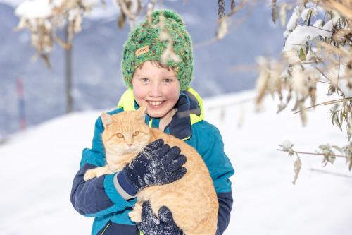 a young boy holding a cat in the snow at Tom's Alpenhütte in Jenig