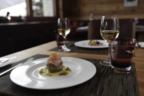 a table with two plates of food and two glasses of wine at The Capra Saas-Fee in Saas-Fee