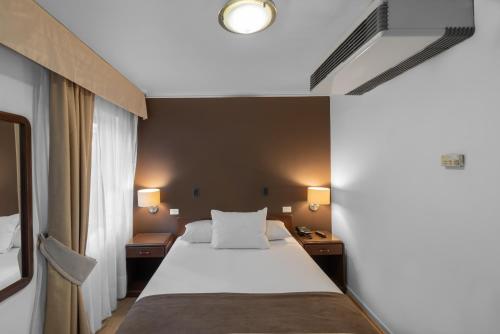 a hotel room with a bed and two night stands at Apart Hotel Elite Las Condes in Santiago
