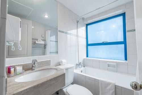 Apart Hotel Elite Las Condes في سانتياغو: حمام مع حوض ومرحاض ونافذة