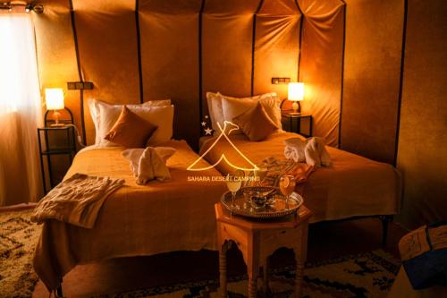 a hotel room with a large bed and a table at Sahara Desert Camping - Luxury Desert Camp Merzouga in Erfoud