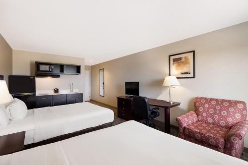 a hotel room with a bed and a chair at Suburban Studios Berwick - Morgan City in Berwick
