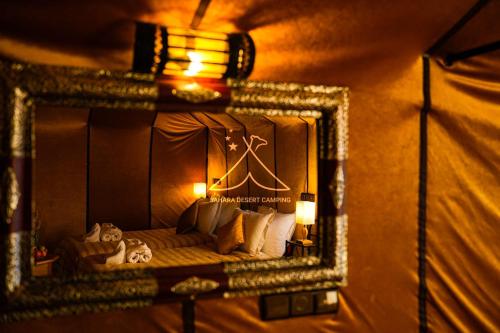 a mirror reflection of a bed in a room at Sahara Desert Camping - Luxury Desert Camp Merzouga in Erfoud