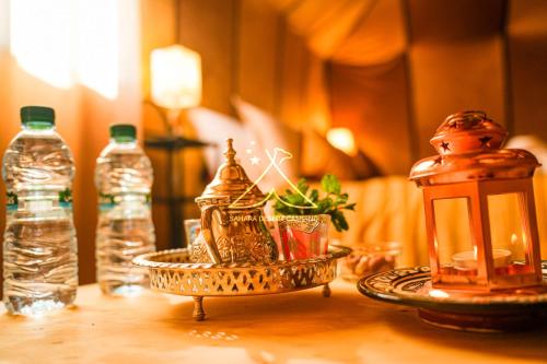 a table with a lantern and bottles of water at Sahara Desert Camping - Luxury Desert Camp Merzouga in Erfoud