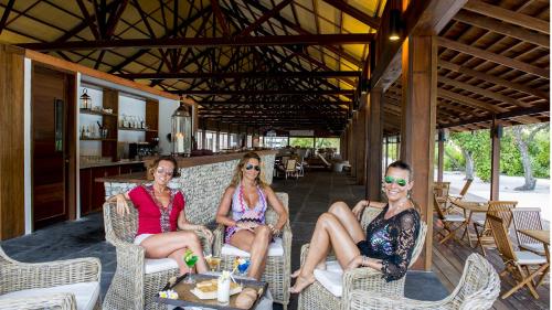 three women sitting in chairs on a patio at The Barefoot Eco Hotel in Hanimaadhoo