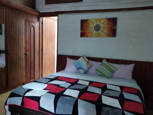 キトにあるHostal La Catolicaのベッドルーム(カラフルなキルトの大型ベッド付)