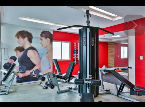 a gym with a man and a woman on a treadmill at Quarto em condomínio beira-mar in Recife