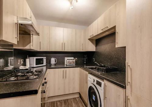 a kitchen with wooden cabinets and a stove top oven at Townhouse Apartment 3 Bedroom High St Montrose in Montrose