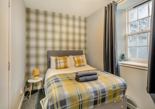 1 dormitorio con 1 cama con manta a cuadros en Townhouse Apartment 3 Bedroom High St Montrose en Montrose