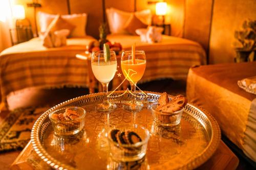 a table with two glasses of champagne and some food at Sahara Desert Camping - Luxury Desert Camp Merzouga in Erfoud