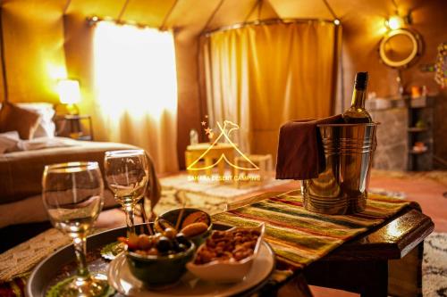 a living room with a table with a bottle of wine at Sahara Desert Camping - Luxury Desert Camp Merzouga in Erfoud
