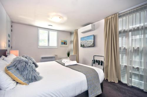 Un dormitorio con una gran cama blanca y una ventana en Lakeshore Studio at the Marina, en Queenstown