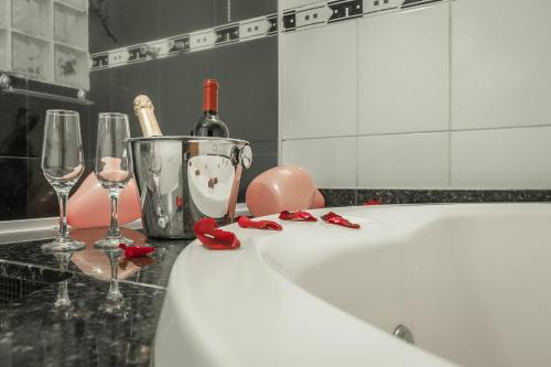 a bathroom with a tub with wine bottles and glasses at Pousada das Nascentes - Brotas in Brotas