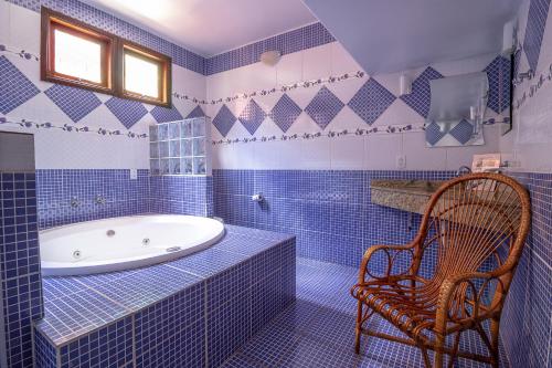a blue tiled bathroom with a tub and a chair at Pousada das Nascentes - Brotas in Brotas