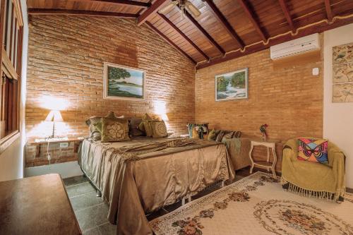 a bedroom with a bed and a brick wall at Pousada das Nascentes - Brotas in Brotas