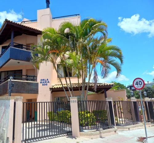 a building with palm trees in front of it at Orla Maria Apartamentos in Florianópolis