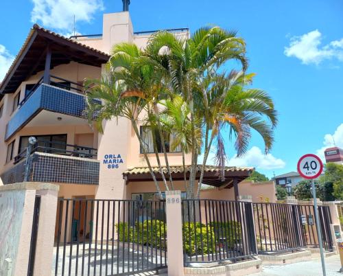 a building with a palm tree in front of it at Orla Maria Apartamentos in Florianópolis