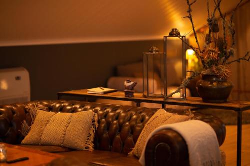 a living room with a leather couch and a table at Mysig lägenhet med öppen planlösning på hästgård. in Ljung