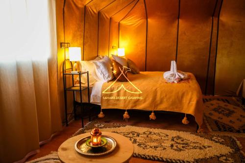 a bedroom with a bed and a table in a room at Sahara Desert Camping - Luxury Desert Camp Merzouga in Erfoud