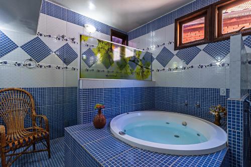 a blue tiled bathroom with a tub and a chair at Pousada das Nascentes - Brotas in Brotas