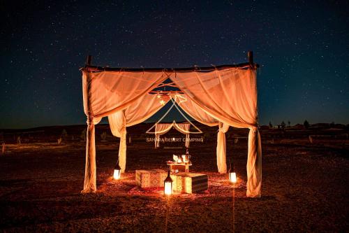 a tent with lights in the middle of the night at Sahara Desert Camping - Luxury Desert Camp Merzouga in Erfoud