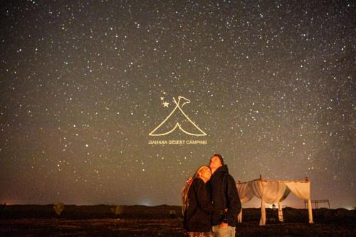 two people standing under a starry night sky at Sahara Desert Camping - Luxury Desert Camp Merzouga in Erfoud