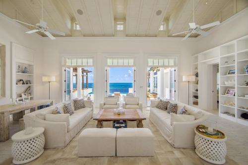 a living room with white furniture and the ocean at Ambergris Cay Private Island All Inclusive in Big Ambergris Cay