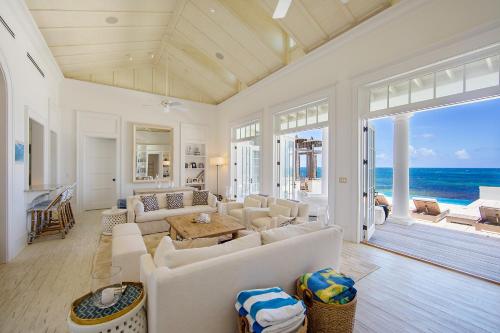 a living room with white furniture and a view of the ocean at Ambergris Cay - Private Island All-Inclusive in Big Ambergris Cay