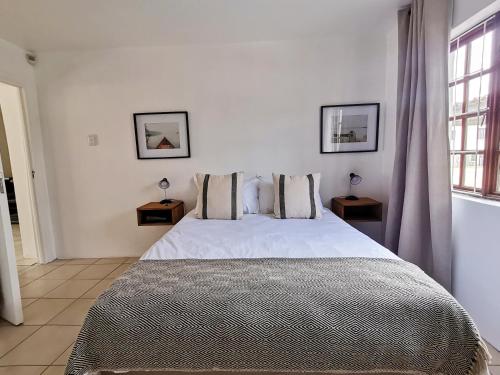 a bedroom with a large white bed with two tables at Beachfront apartment in a secure complex in Port Alfred