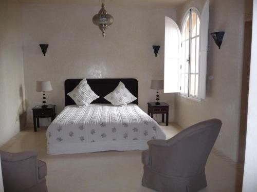 Palais Villa Talaa Resort في تارودانت: غرفة نوم بسرير ابيض وكرسيين