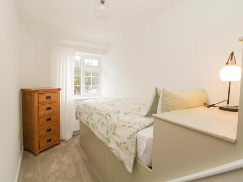 a white bedroom with a bed and a dresser at Blacksmiths Cottage in Northallerton