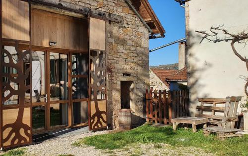 een gebouw met een houten deur en een houten bank bij L'Oseraie du Quercy in Calvignac