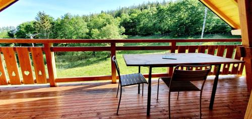 een houten terras met een tafel en twee stoelen bij Gîte *** du Gazon du Cerisier in Le Tholy