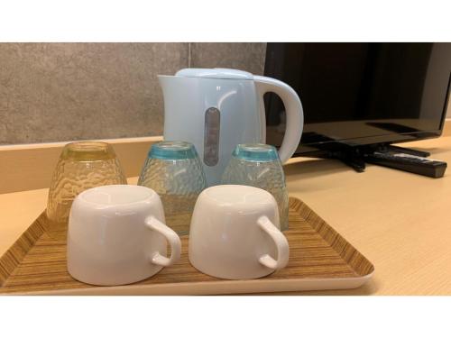 a tray with three cups and a tea kettle at On the Beach Lue - Vacation STAY 91578v in Sesoko