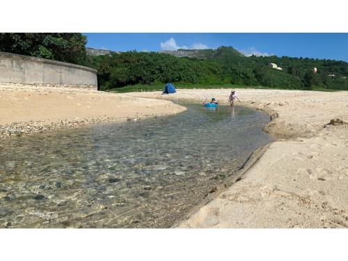 two people playing in the water on a beach at On the Beach Lue - Vacation STAY 91578v in Sesoko