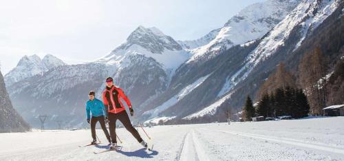 a man and woman on skis in the snow with mountains at Pension Alpina in Roppen