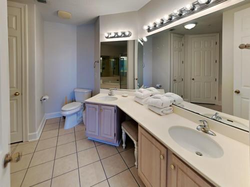 a bathroom with two sinks and a mirror and a toilet at Regency Isle #609 in Orange Beach