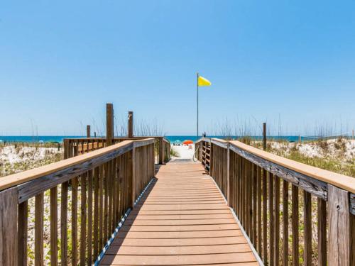 a wooden bridge over a beach with a flag on it at Regency Isle #609 in Orange Beach