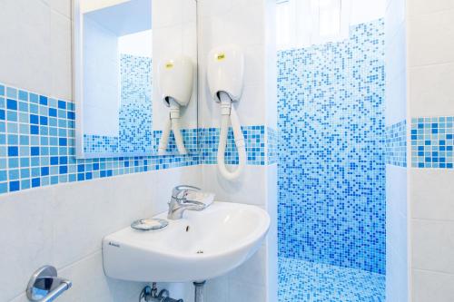 uma casa de banho azul e branca com um lavatório e um espelho em NOIDUE Hotel em Rimini