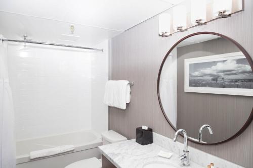 a white bathroom with a mirror and a sink at Sandman Signature Lethbridge Lodge in Lethbridge