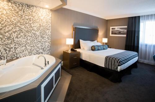 a hotel room with a bed and a bath tub at Sandman Signature Lethbridge Lodge in Lethbridge