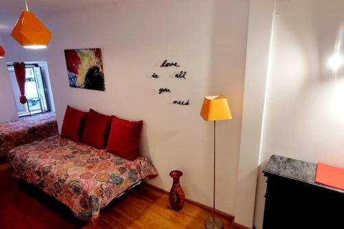 - une chambre avec un lit doté d'oreillers rouges et d'une lampe dans l'établissement Setúbal RP House apartamento perto do mar e comércio na Luisa Todi, à Setúbal